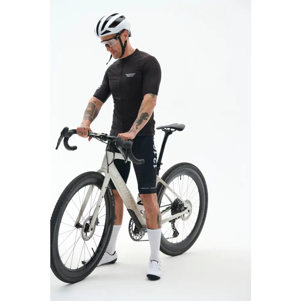 Cyclist in black TwelveSixteencycling outfit with helmet and bike 