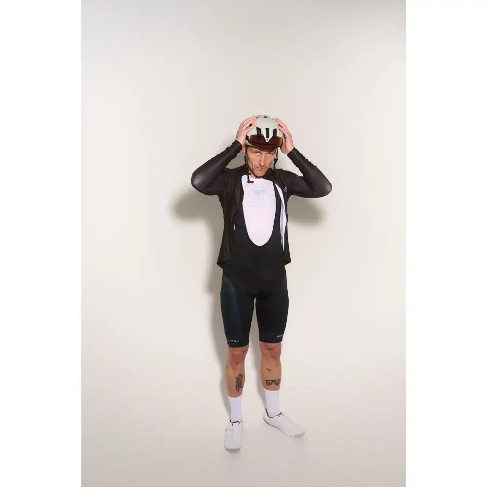 Person wearing a black cycling suit and helmet, and white baselayer