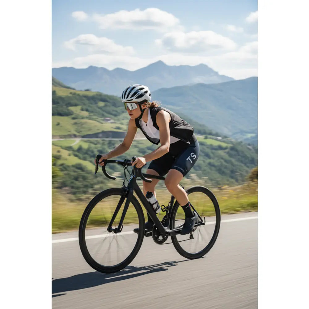 Person cycling on a road with mountains in the background